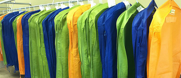 Assorted colors of Green Garmento bags hanging on clothes line.
